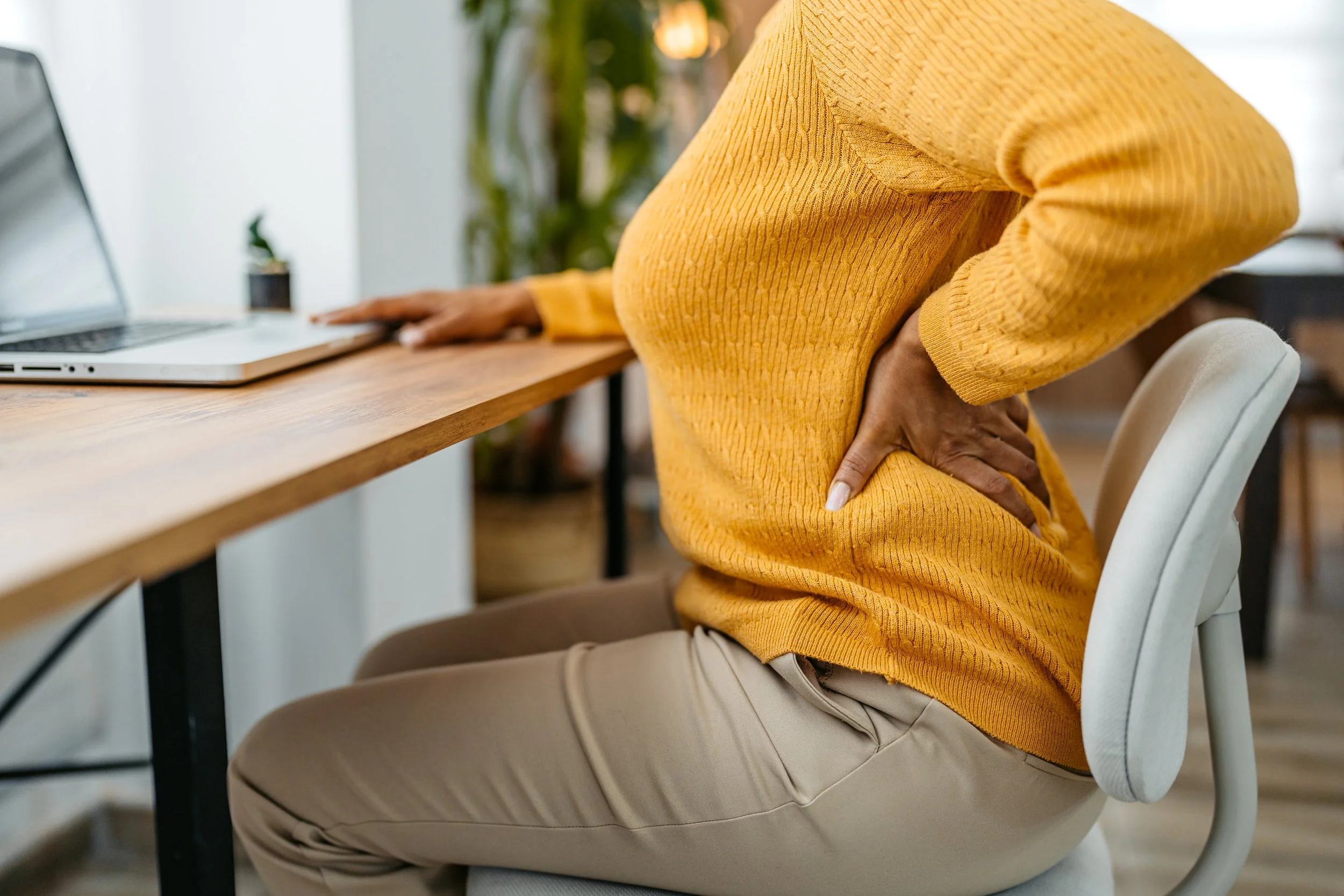 Person experiencing back pain at a desk — a common reason patients seek chiropractic care
